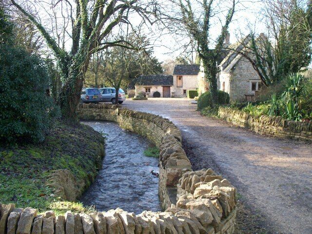 River Coln at Syreford The infant River Coln runs alongside the road in this attractive village. The river has just passed under a bridge which has taken it from one side of the road to the other.