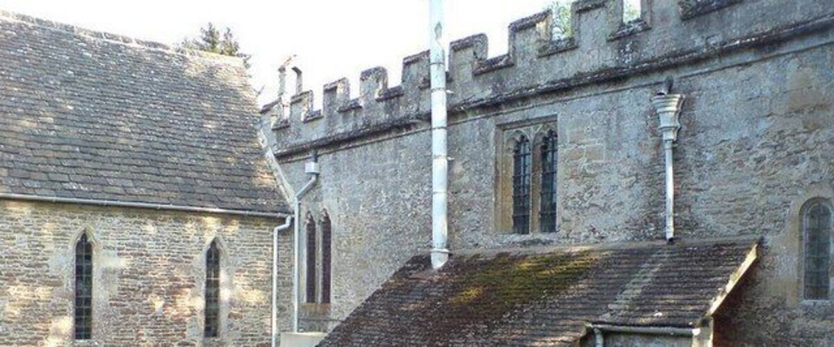 A stone church with a small bell tower and a grassy courtyard.