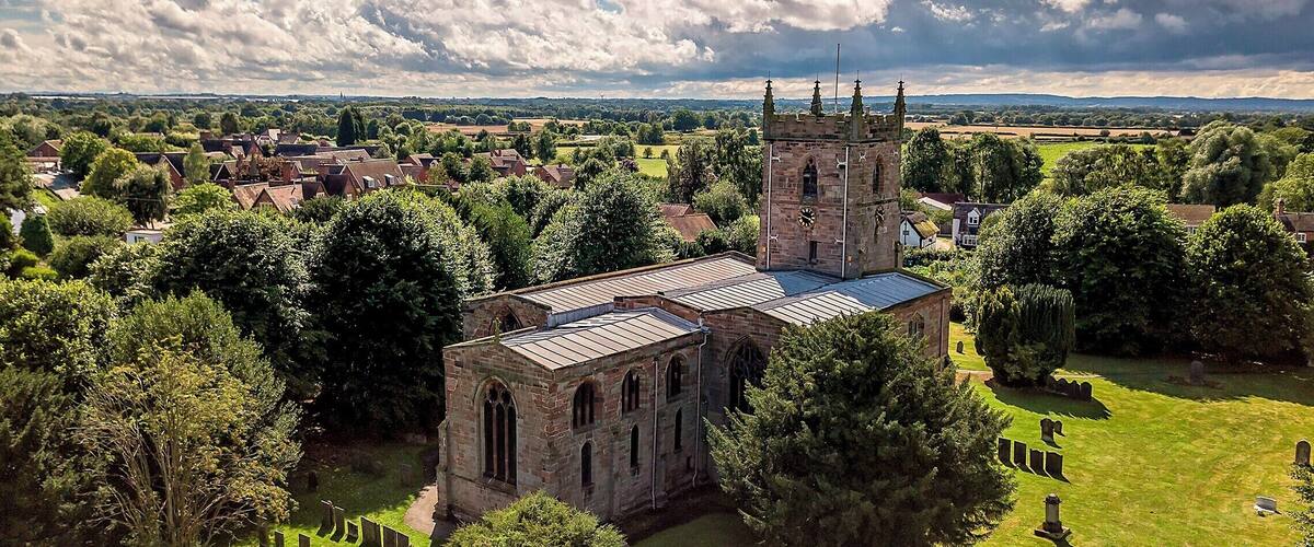 A historic church with a tower, surrounded by a cemetery and lush greenery.