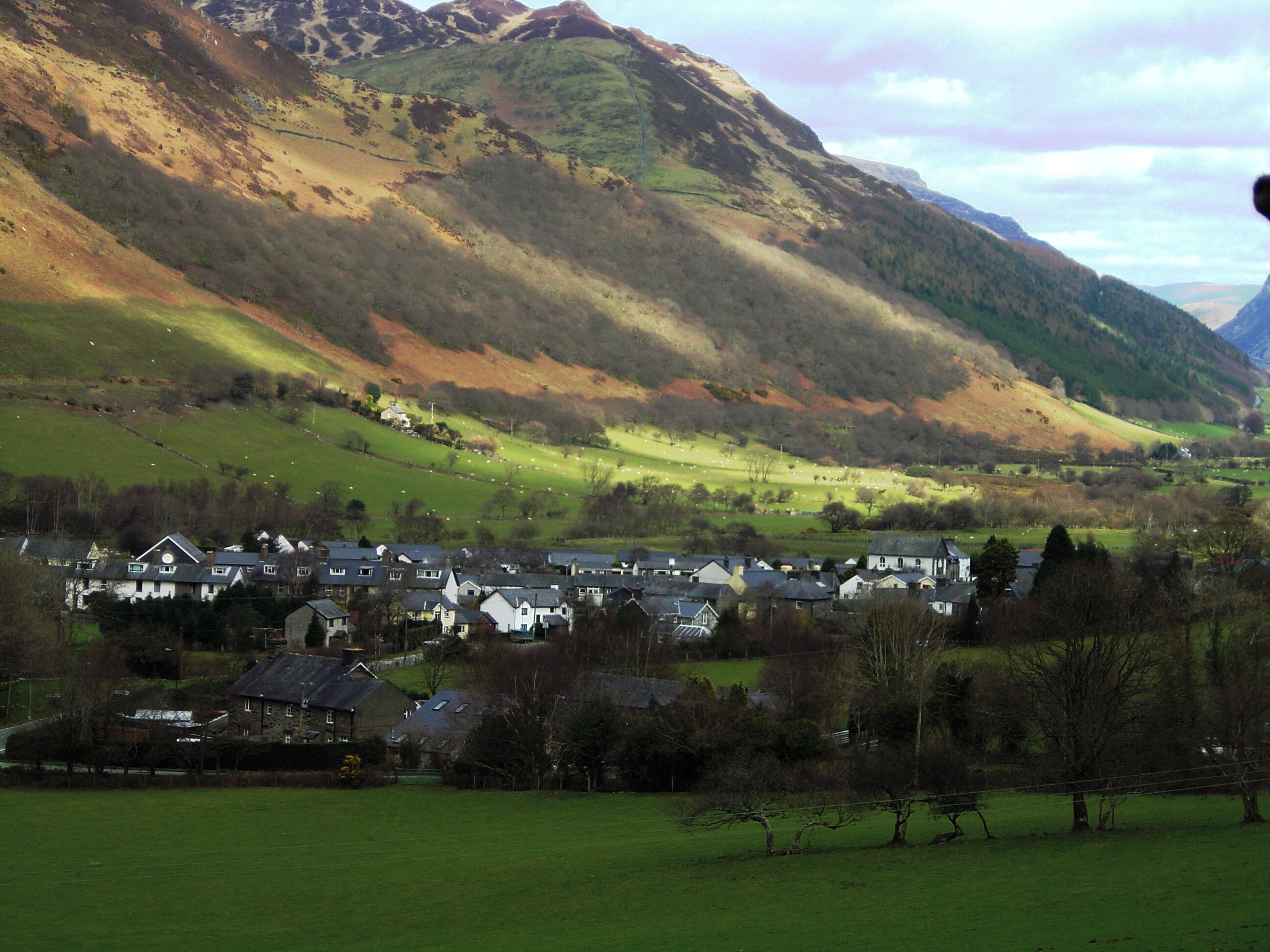 A valley with a small town nestled among rolling hills and mountains.