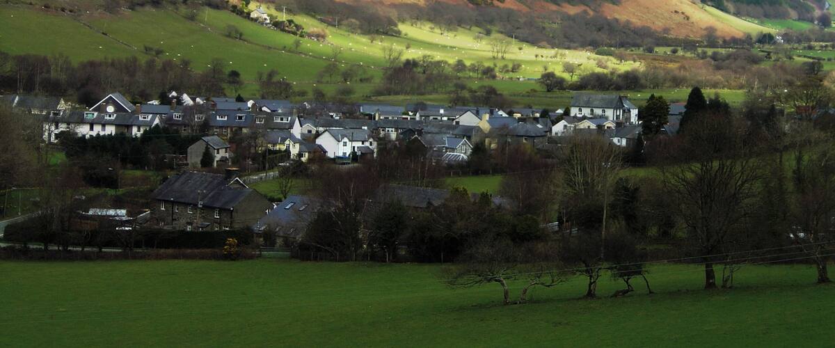 A valley with a small town nestled among rolling hills and mountains.