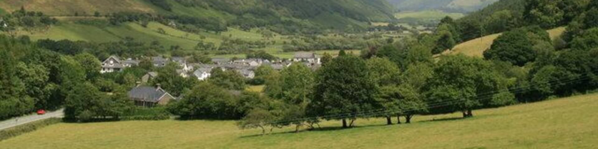The village of Abergynolwyn, Gwynedd. Abergynolwyn and the valley beyond taken from the Talyllyn railway walk near Abergynolwyn station. On the left is the B4405 heading towards Dolgellau.