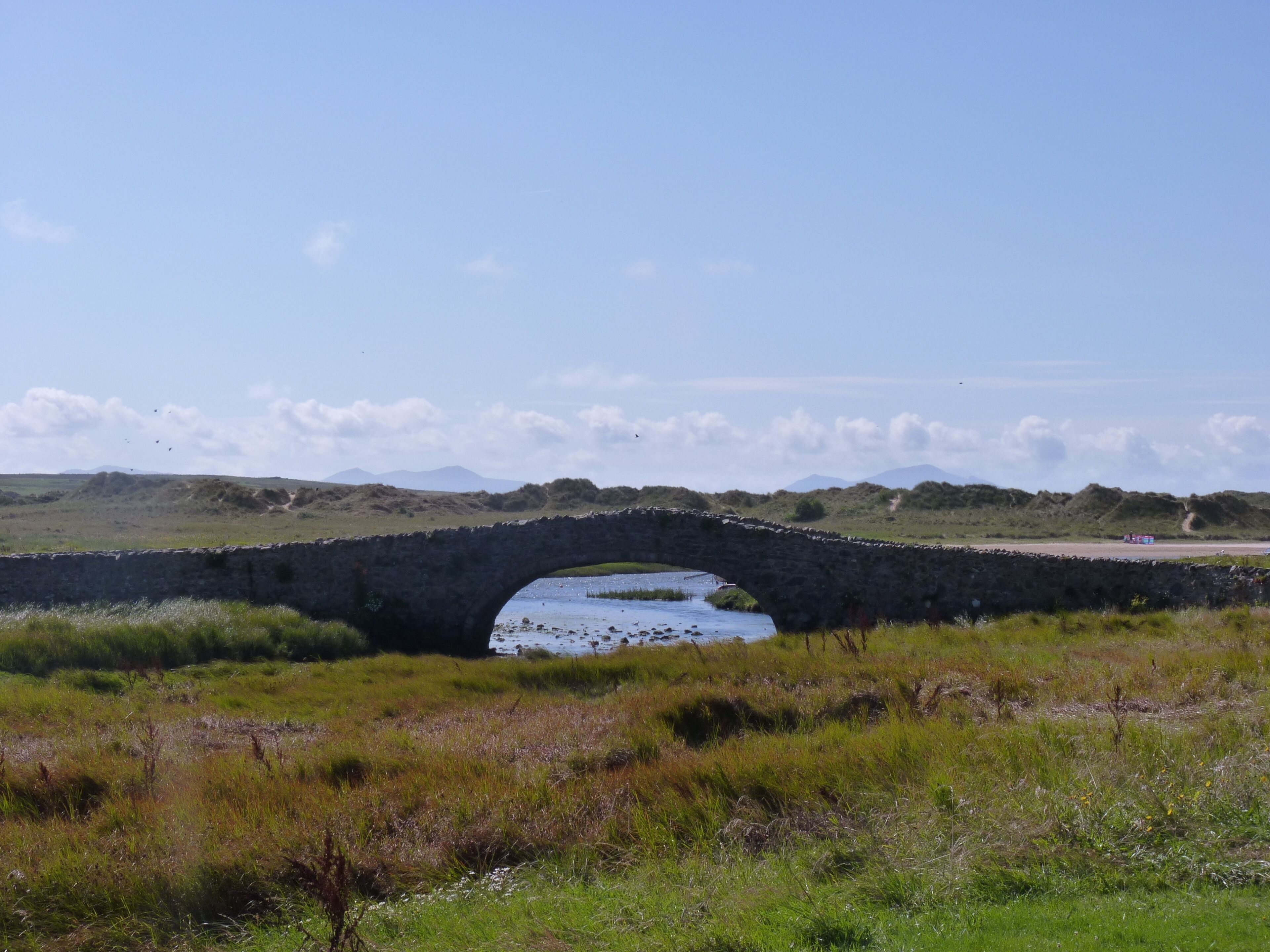 Medieval bridge over the Afon Ffraw at Aberffraw.The large expanse of sands is crossed by the road to the east.