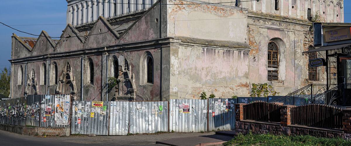 An old, weathered building with arched windows and a bell tower.