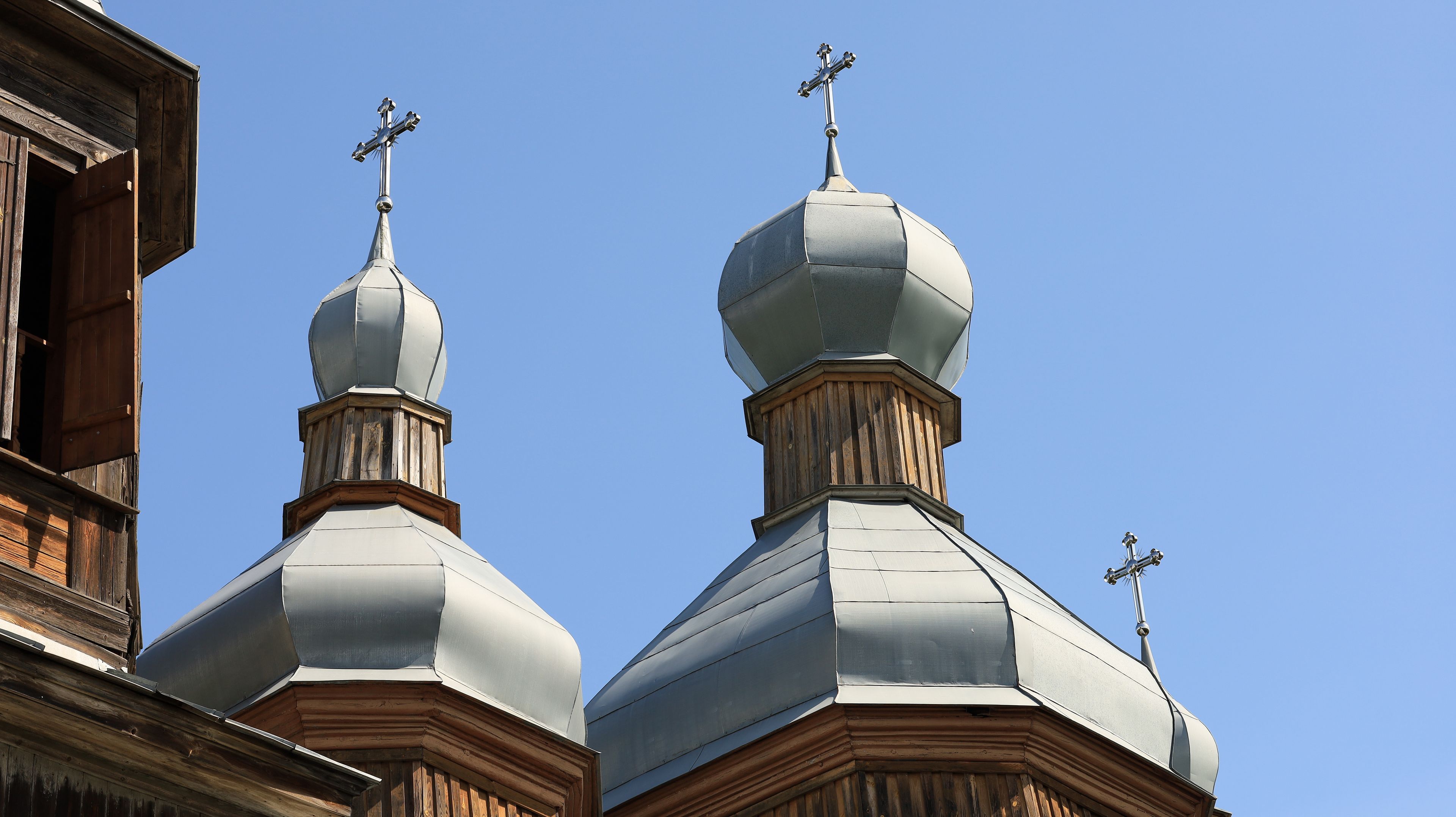 Deux coupoles d’église, surmontées de croix, se dressent sur un ciel bleu dégagé.