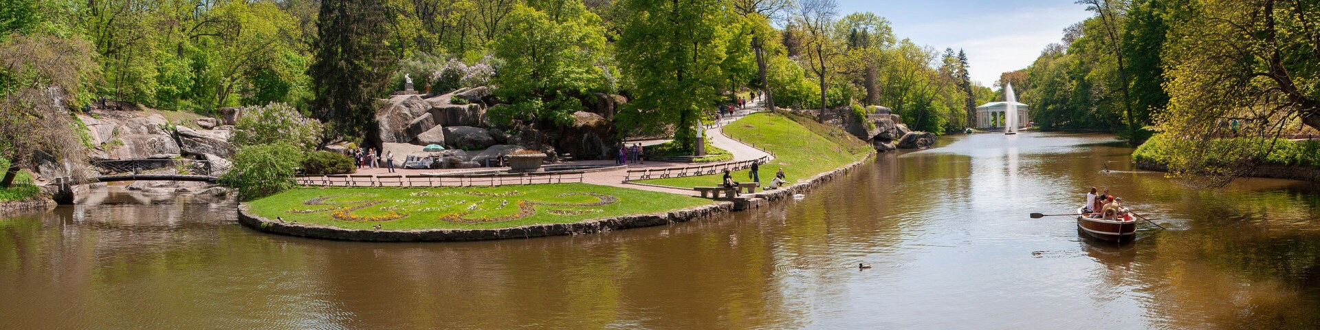 Um parque com lago, gazebo e estátua.