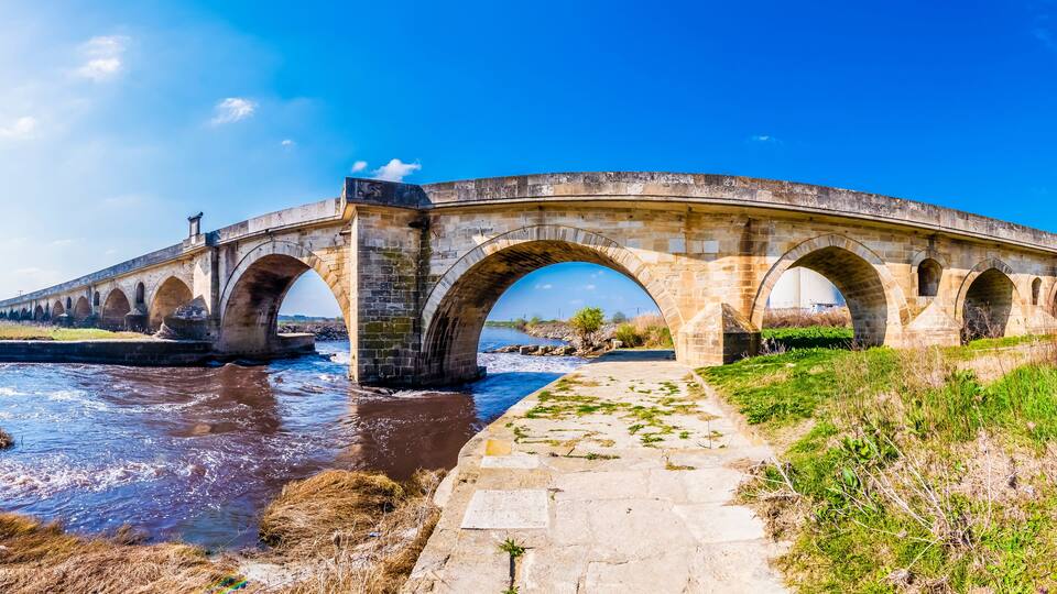 A stone bridge over a river with a clear blue sky.