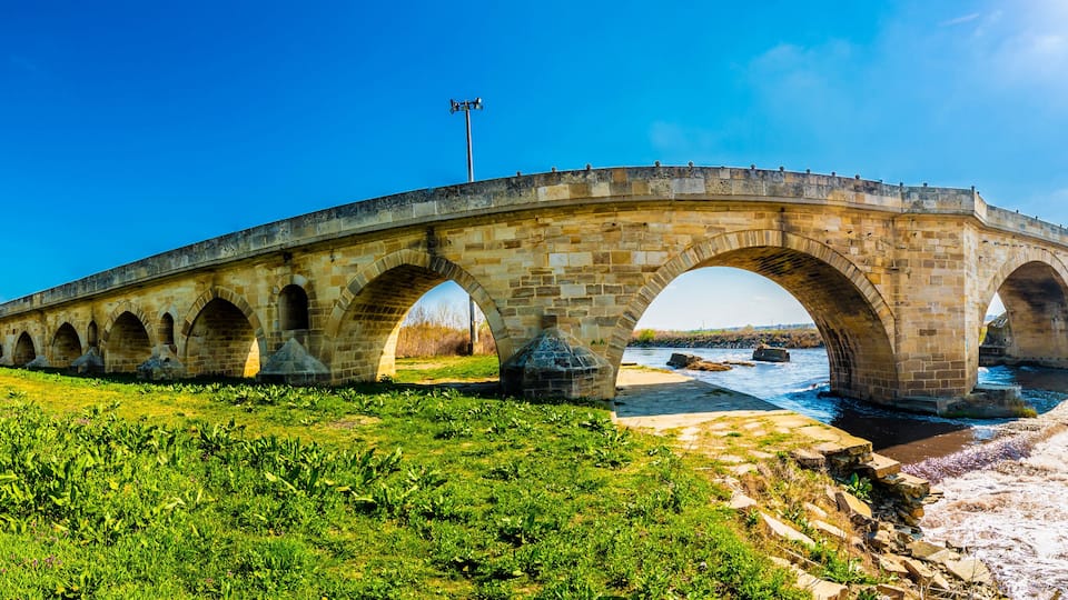 A stone bridge with multiple arches over a river.
