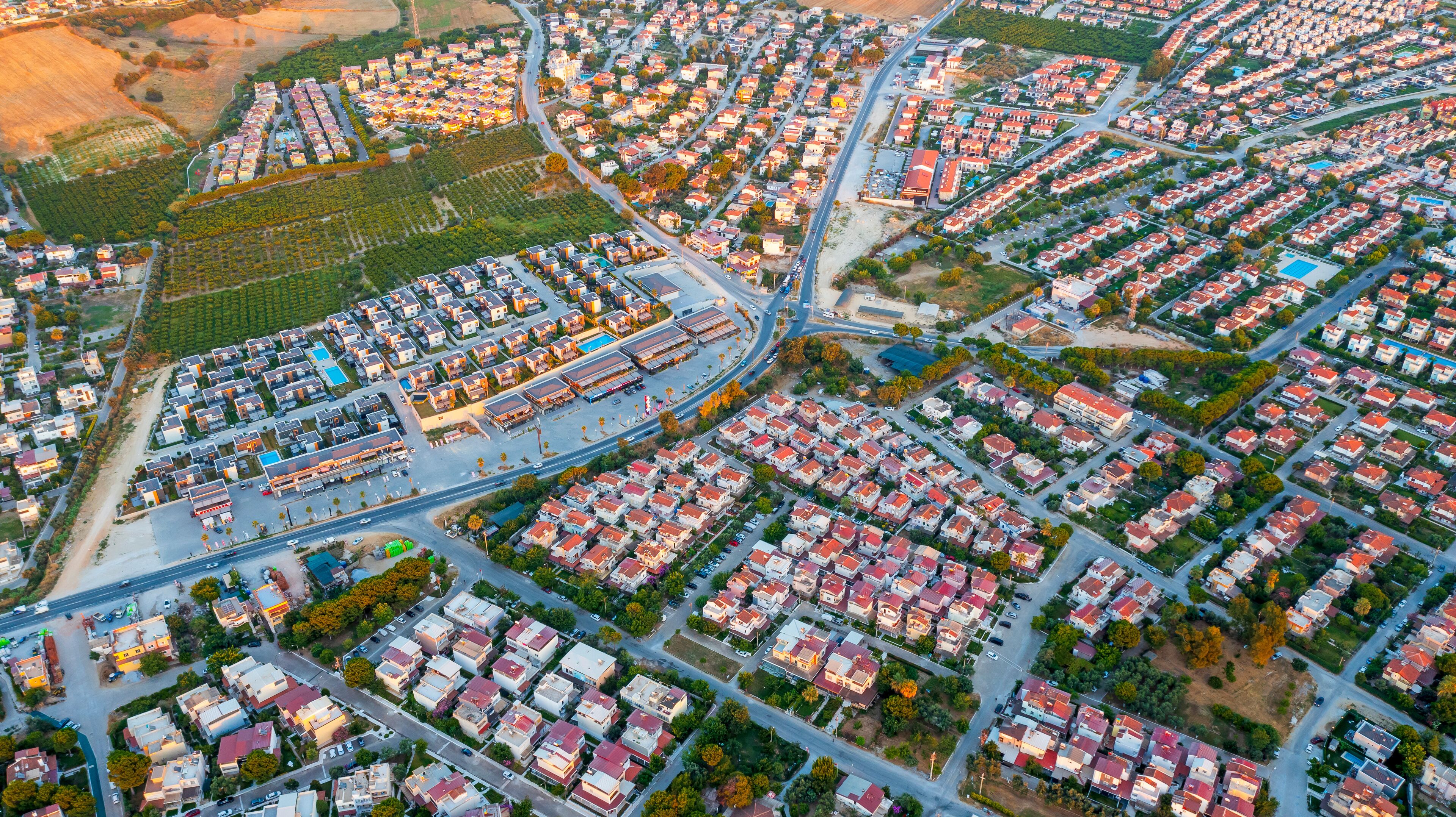An aerial view of a residential area with organized housing, roads, and green spaces.