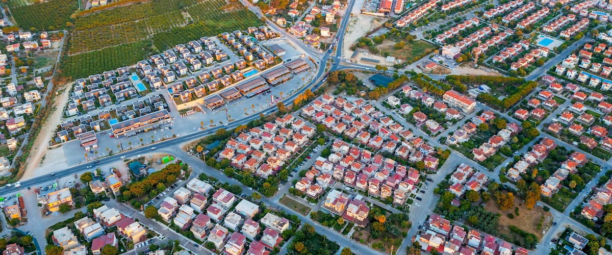An aerial view of a residential area with organized housing, roads, and green spaces.
