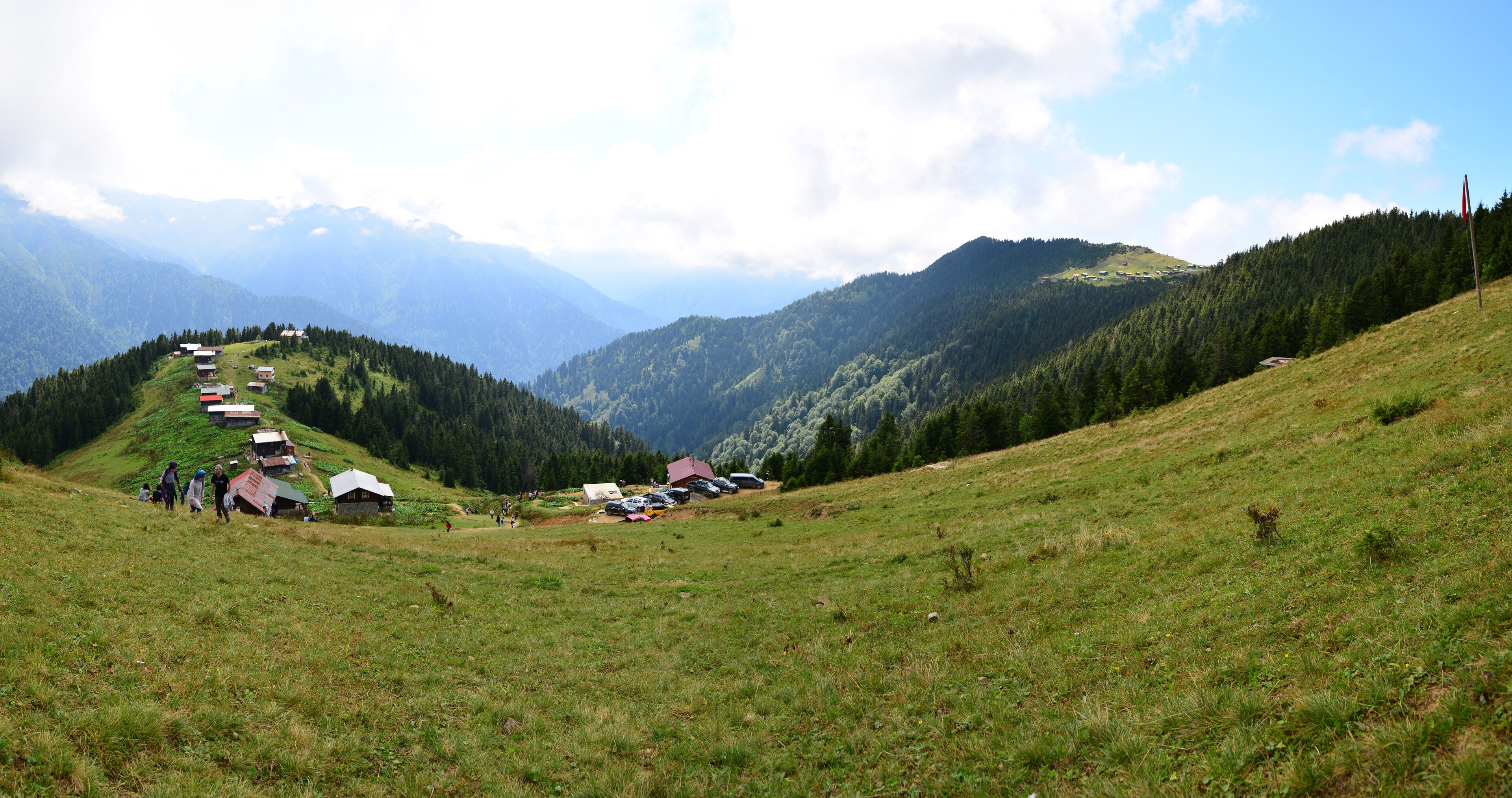 A mountainous landscape with a row of houses on a hillside, a clear sky, and distant mountains.