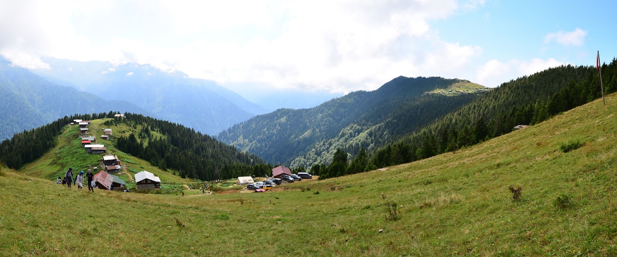 A mountainous landscape with a row of houses on a hillside, a clear sky, and distant mountains.