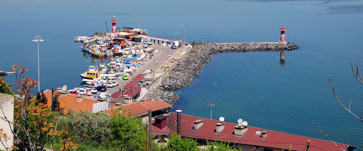 A harbor with boats, a lighthouse, and buildings along the shore.