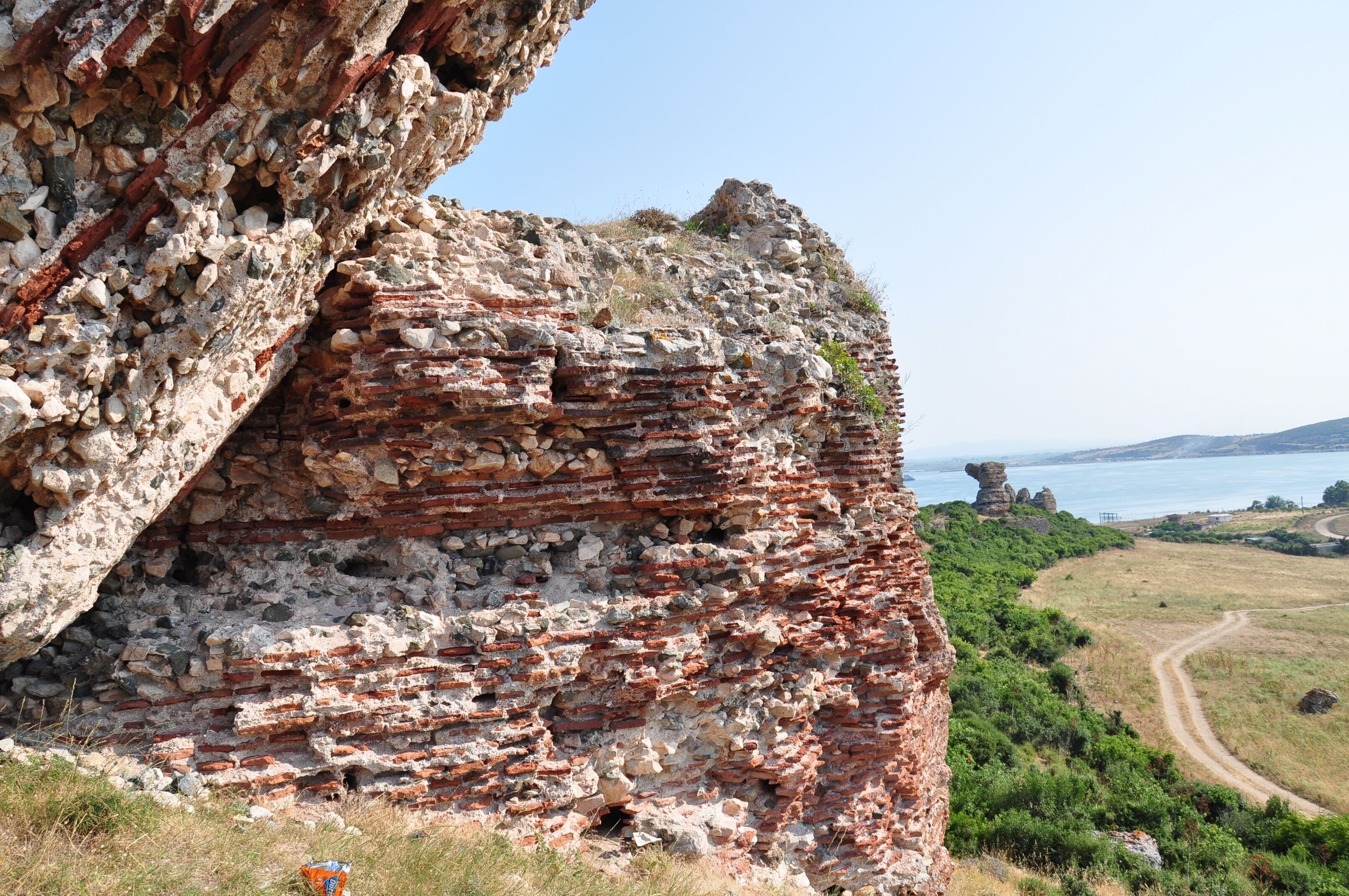 A cliff with ancient brick ruins and a coastal view.