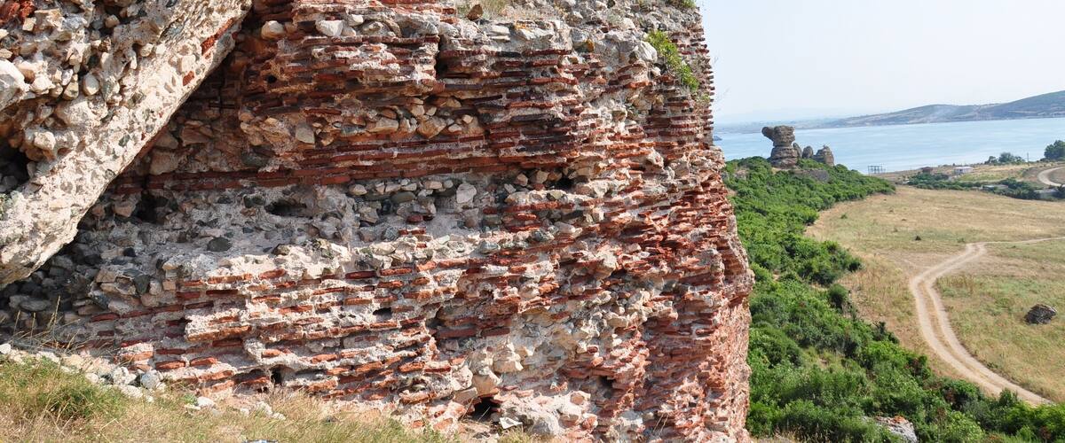 A cliff with ancient brick ruins and a coastal view.