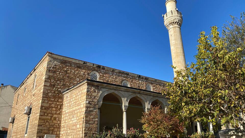 A historic mosque with a tall minaret and arched entrance.