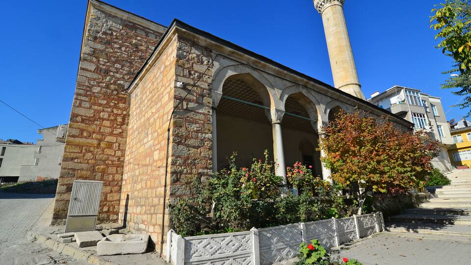 A historic building with a stone facade, arched windows, and a tall minaret.