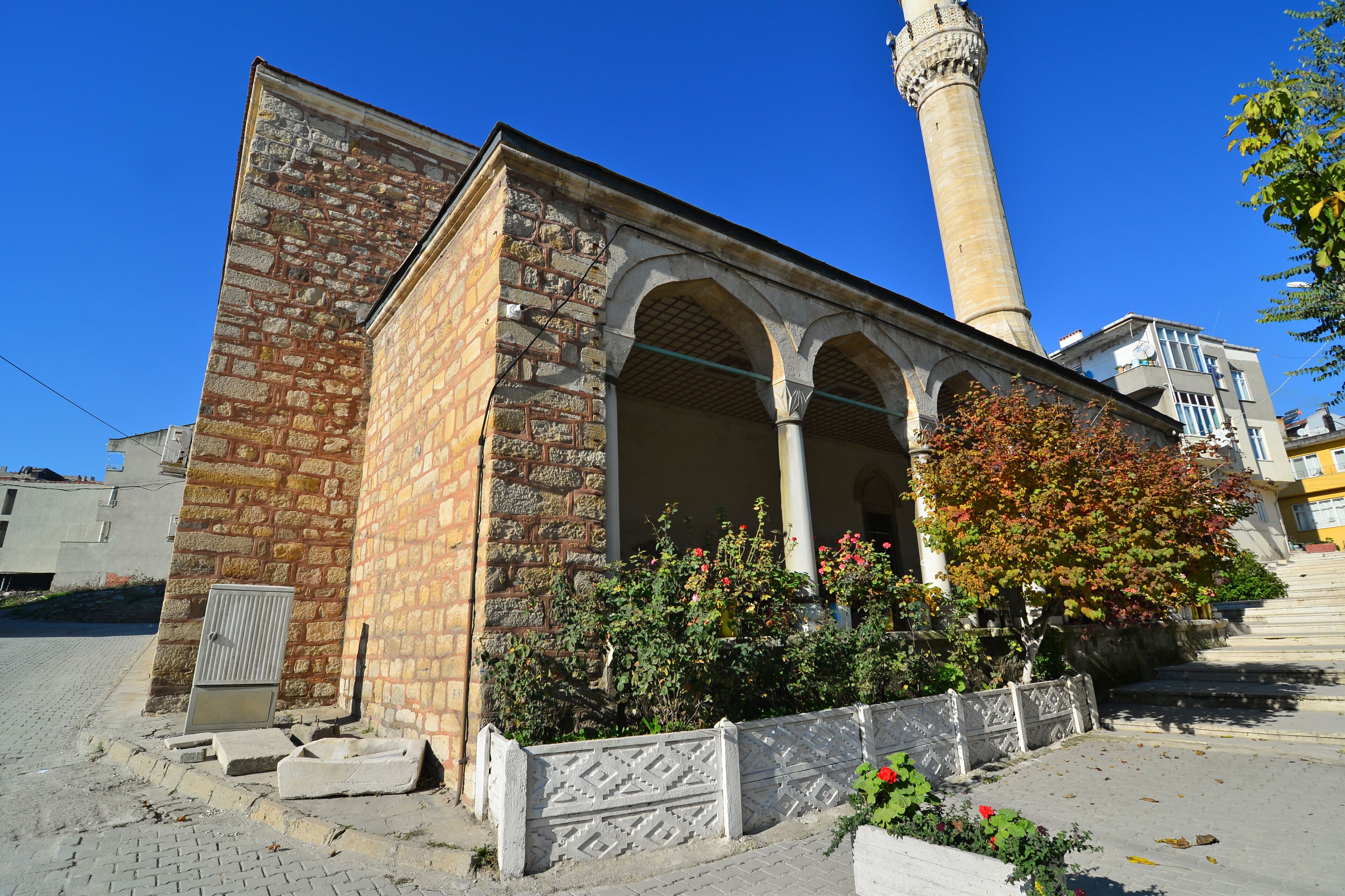A historic building with a stone facade, arched windows, and a tall minaret.