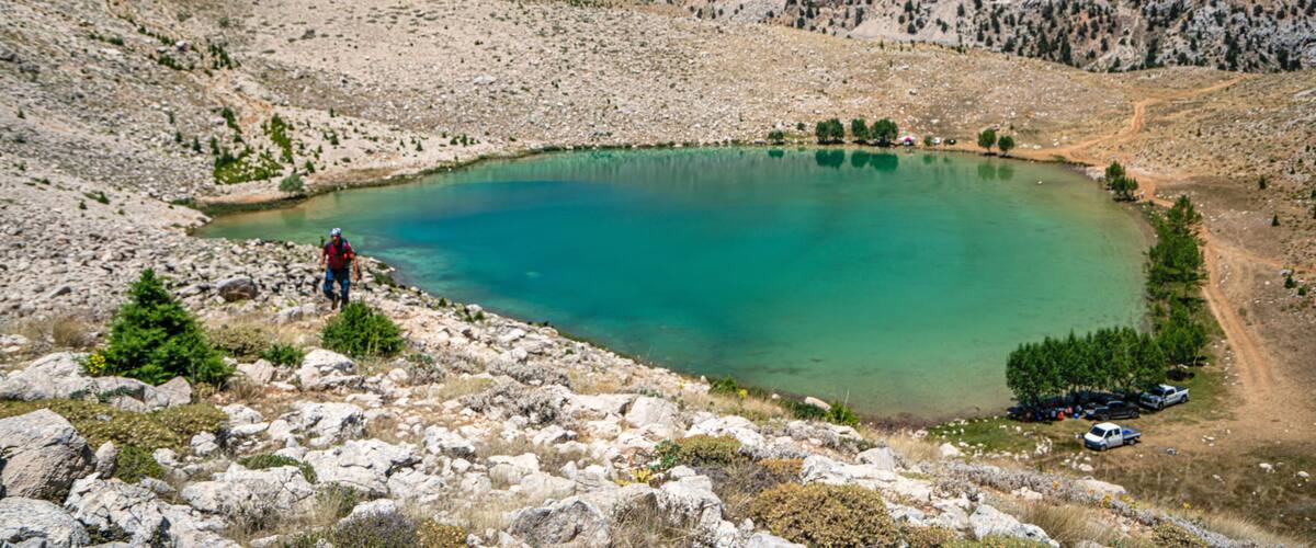A mountainous landscape with a turquoise lake surrounded by rocky terrain and sparse vegetation.