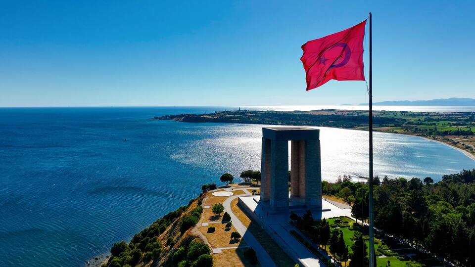 A coastal landscape with a monument and a flag.