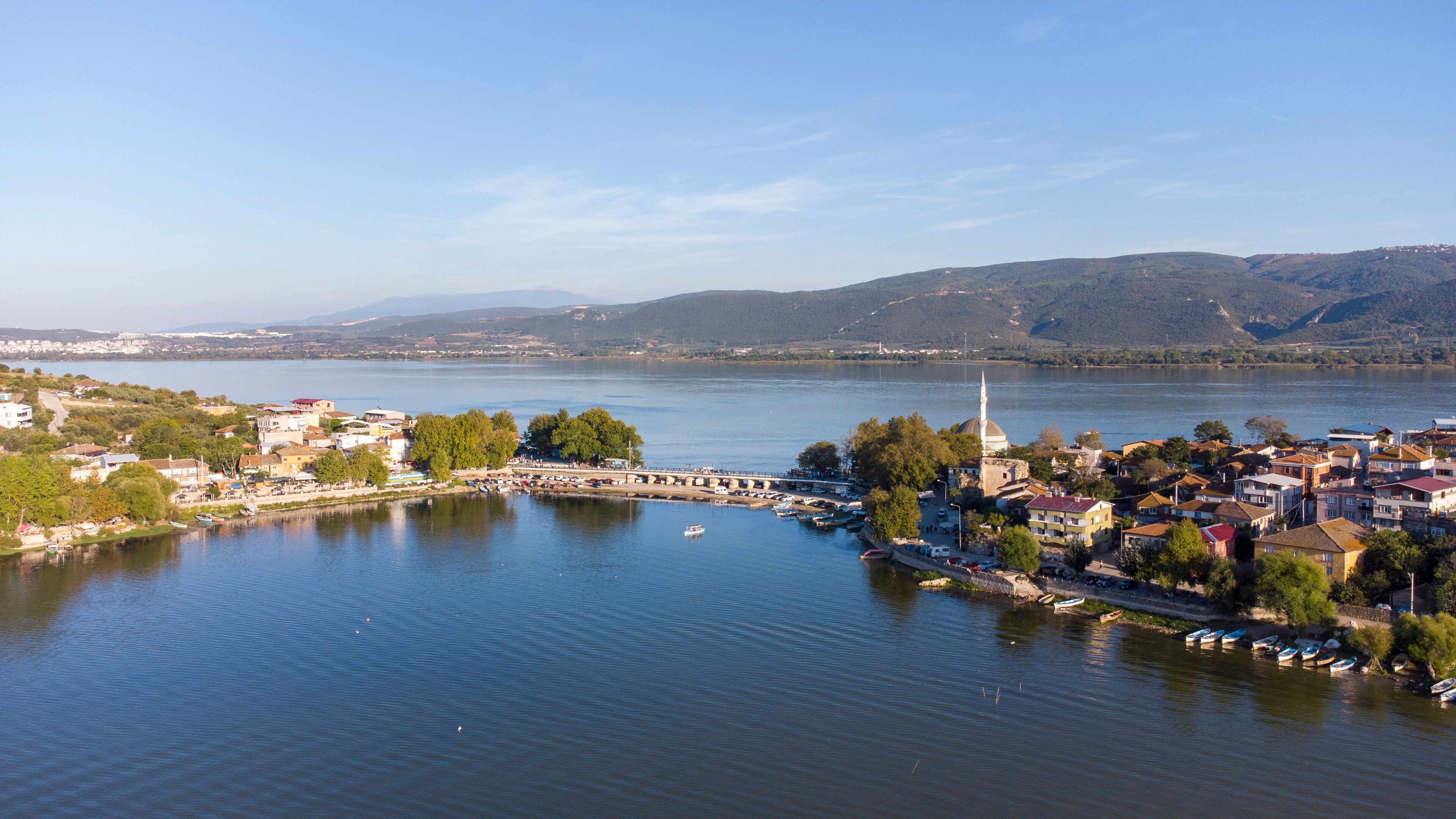 A river with boats, a bridge, and a town with buildings and a mosque.