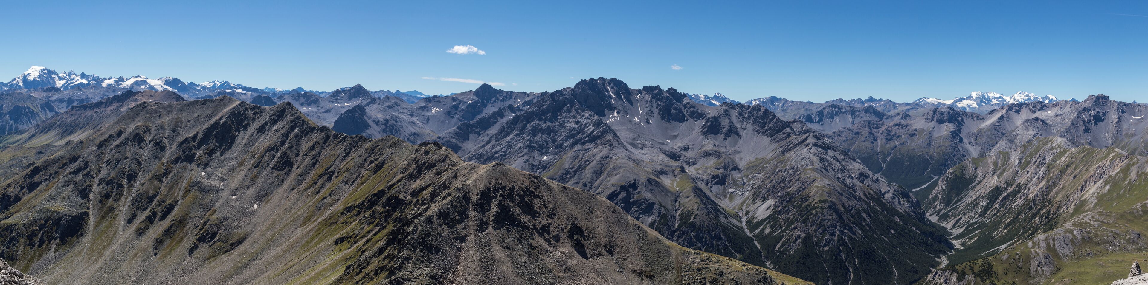 Panoramic view south to west from Piz Daint summit; in the background Ortler (left) and Bernina massifs; in the center Piz Murtaröl, to its right the lower part of Val Mora.