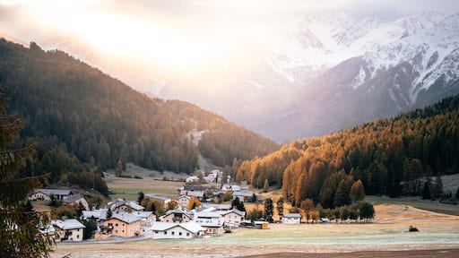A village nestled in a valley with snow-capped mountains in the background.