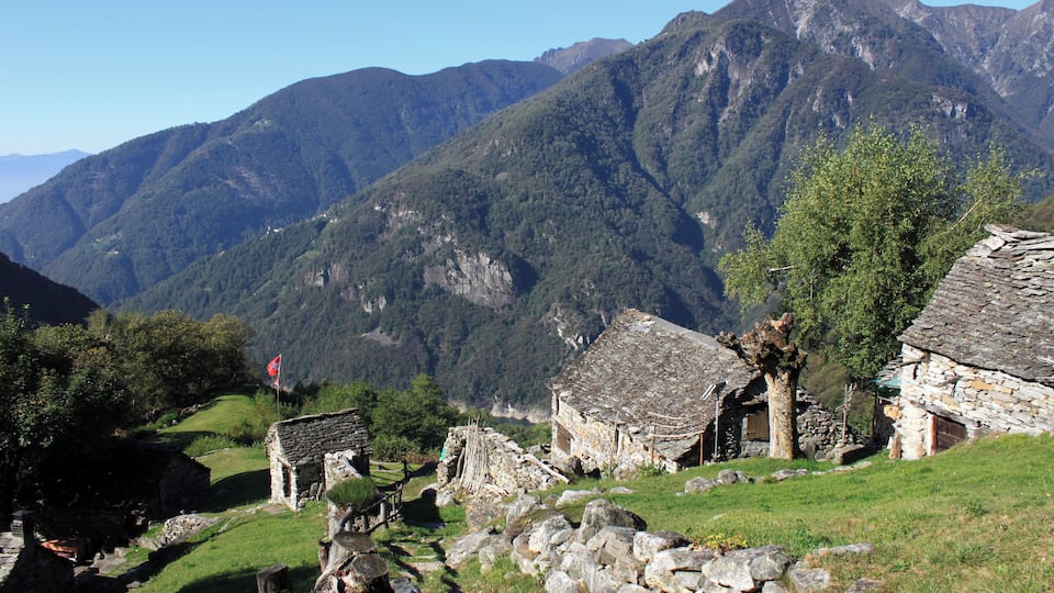 A mountainous landscape with traditional stone houses and a flag.