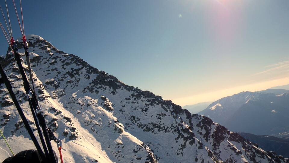 A snowy mountain peak with a clear sky and distant mountains.