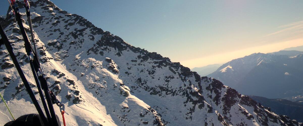 A snowy mountain peak with a clear sky and distant mountains.