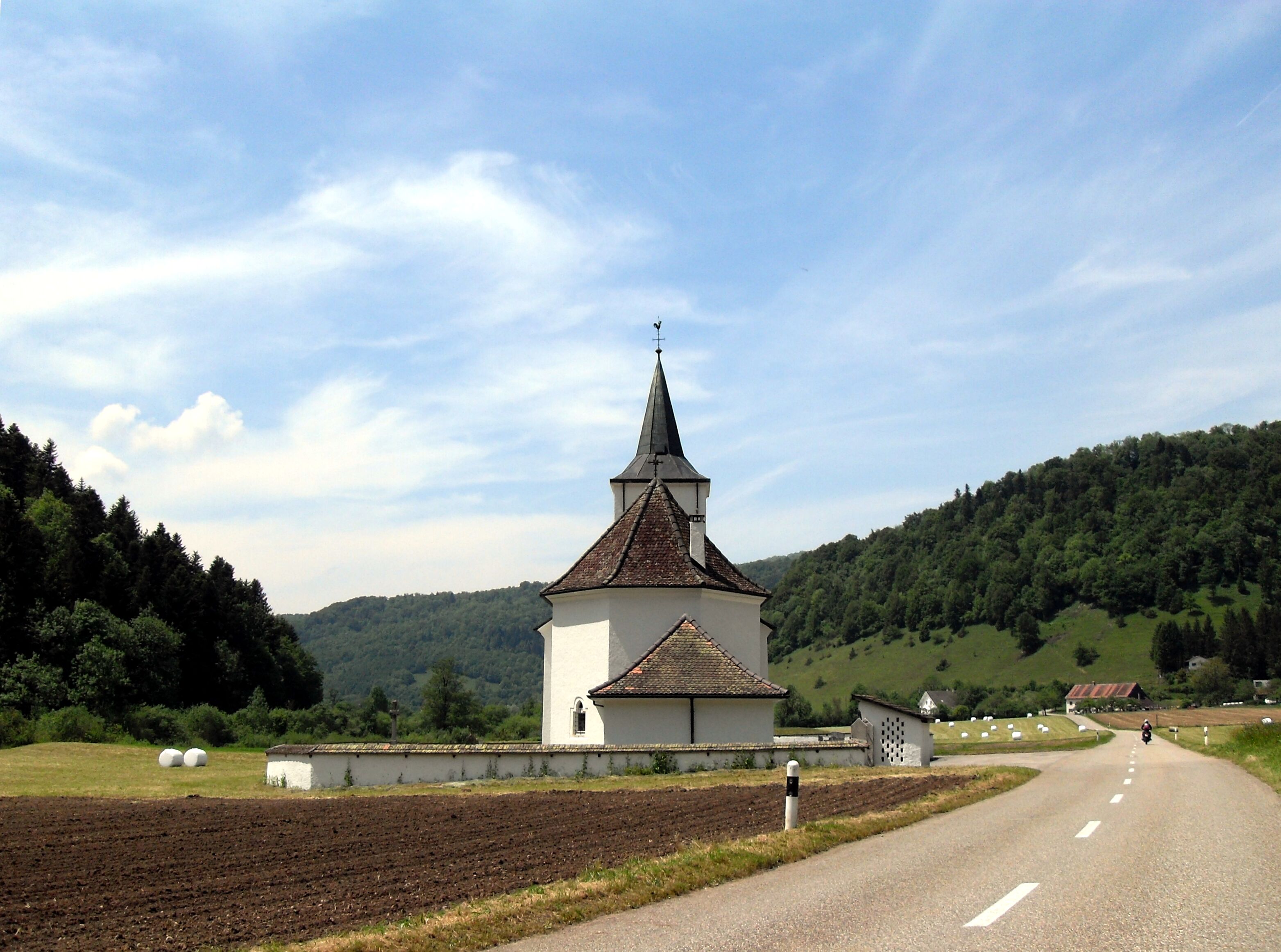 A church with a tall steeple in a rural setting.