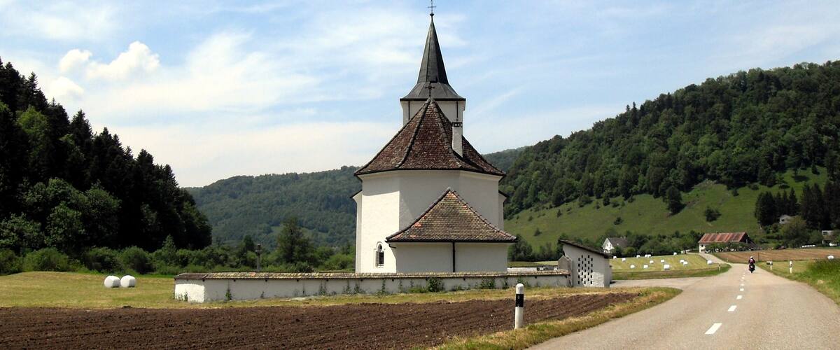 A church with a tall steeple in a rural setting.