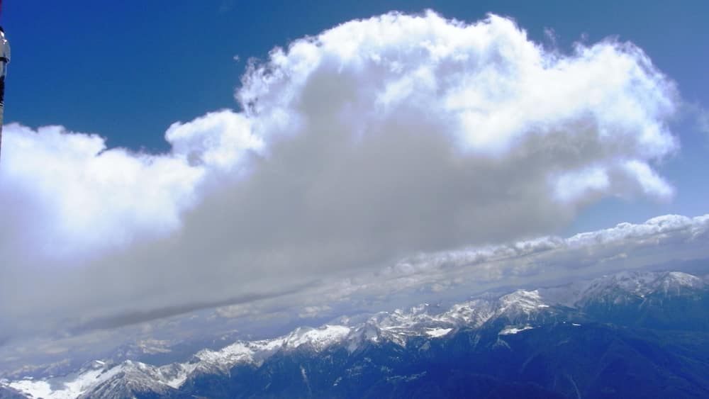 A snow-covered mountain range under a partly cloudy sky.
