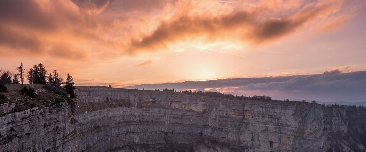 A canyon with layered rock formations and a sunset in the background.