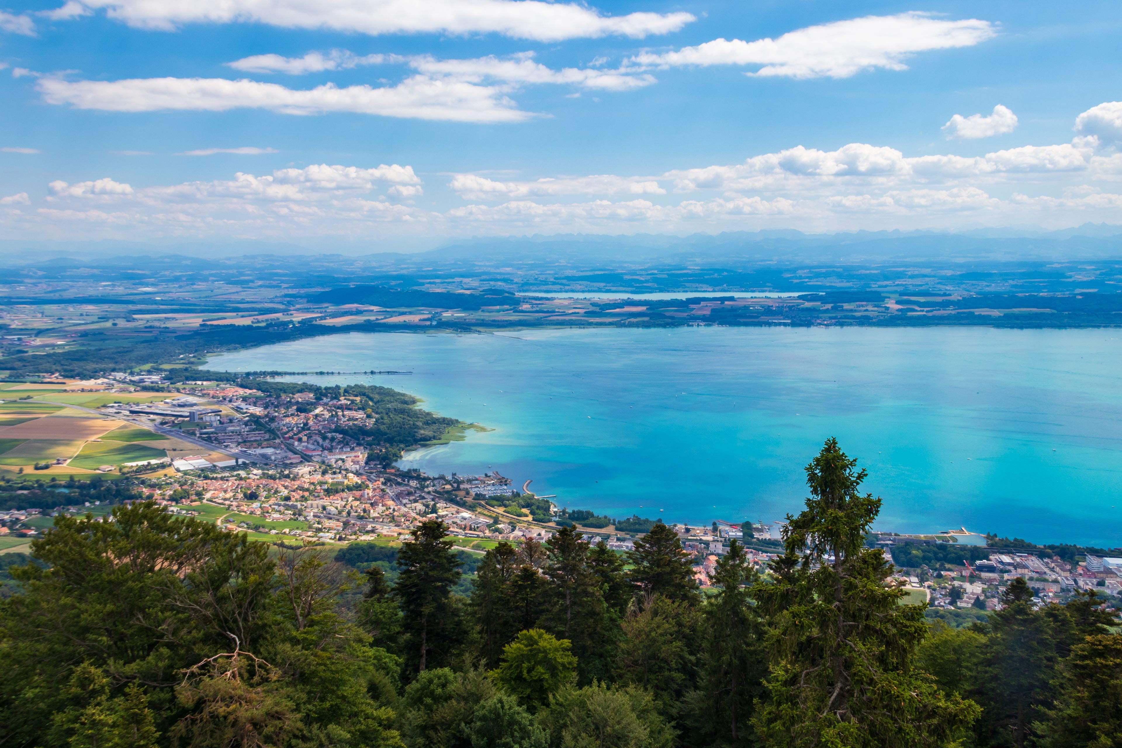Paisagem costeira com uma grande massa de água, uma cidade na orla e colinas ao redor.