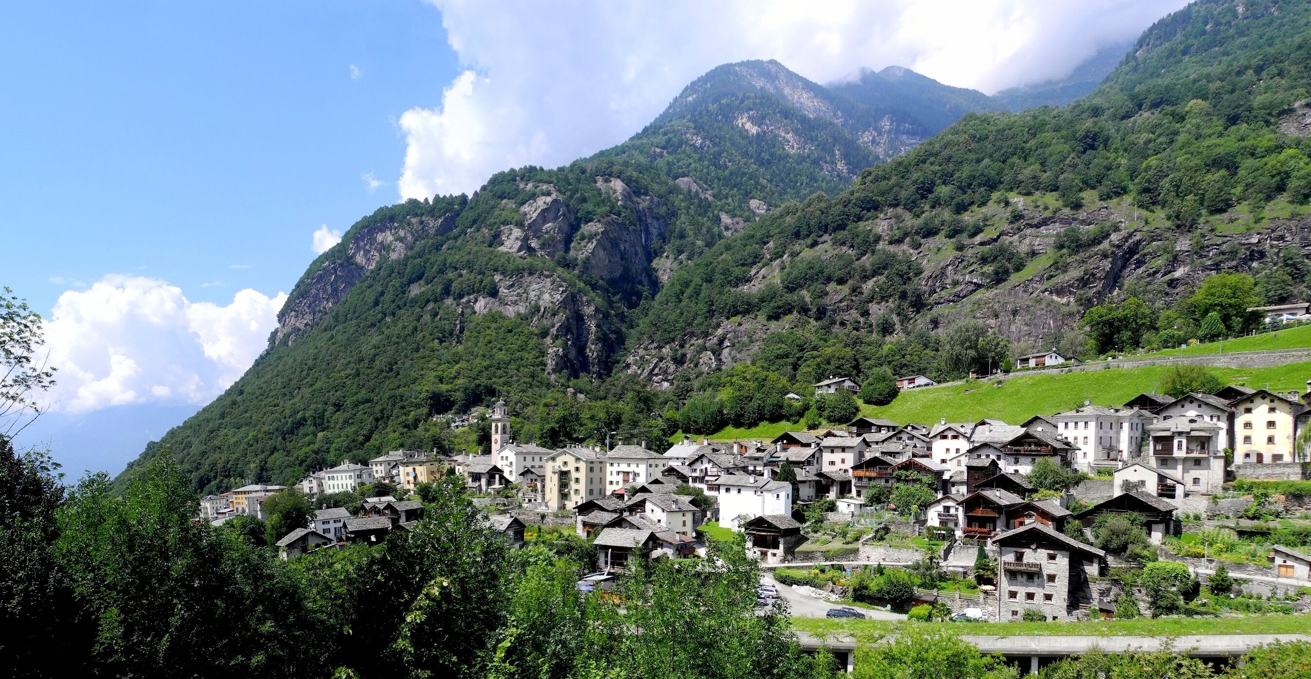 A mountainous village with traditional houses nestled among lush greenery and rocky cliffs.