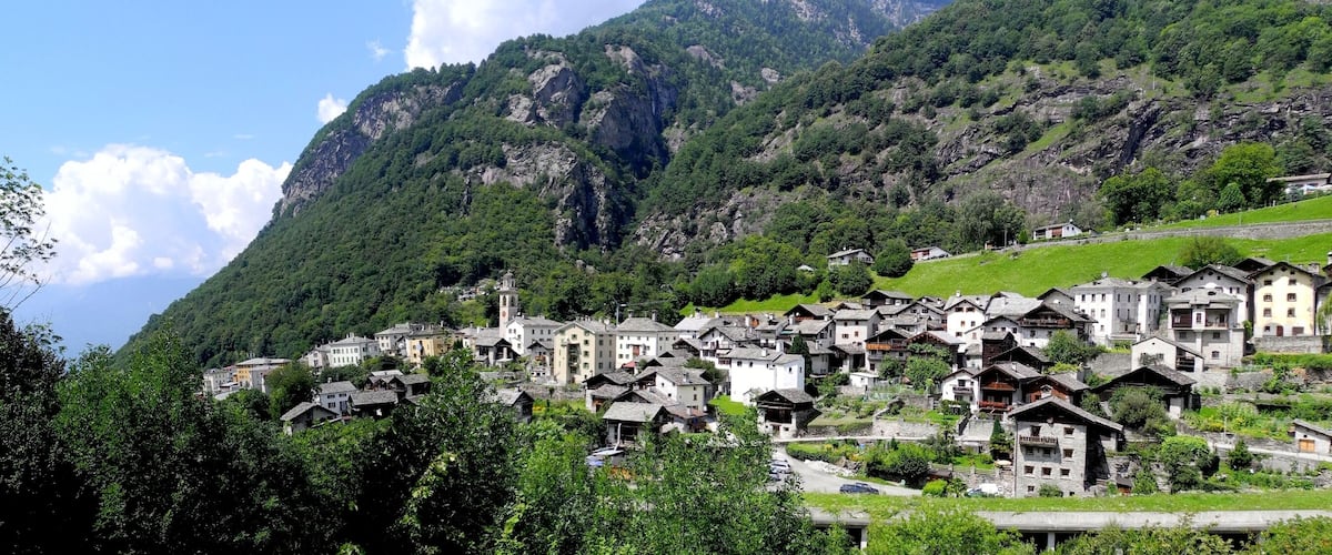 A mountainous village with traditional houses nestled among lush greenery and rocky cliffs.