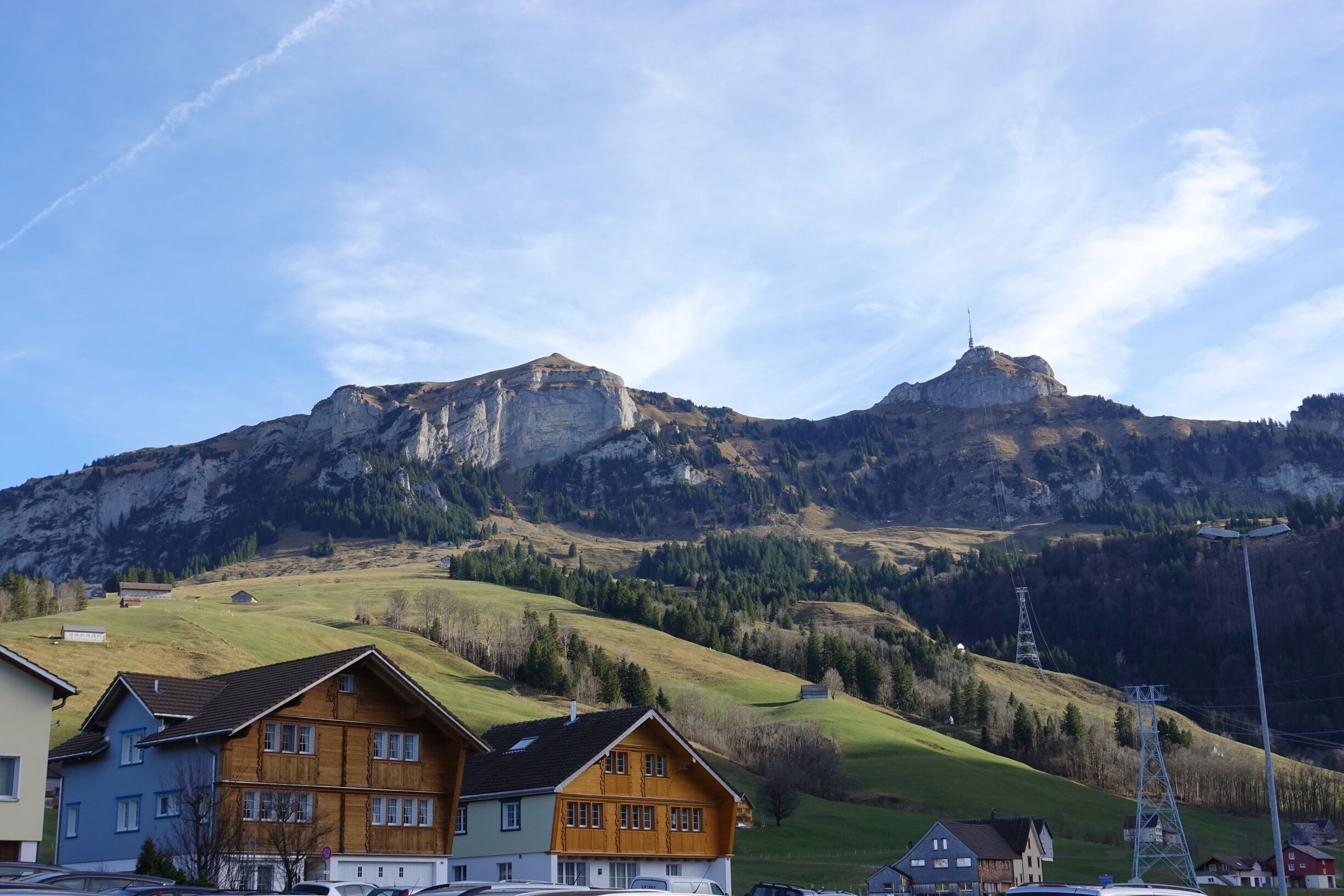 A mountain with a prominent peak, a valley with houses, and a clear sky.