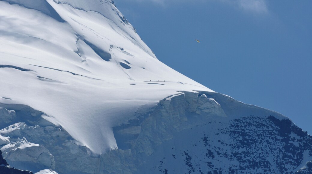 Switzerland, Graubünden, a Heli Bernina Eurocopter AS 350 overhead 3 mountaineers below Bellavista, seen from Diavolezza.