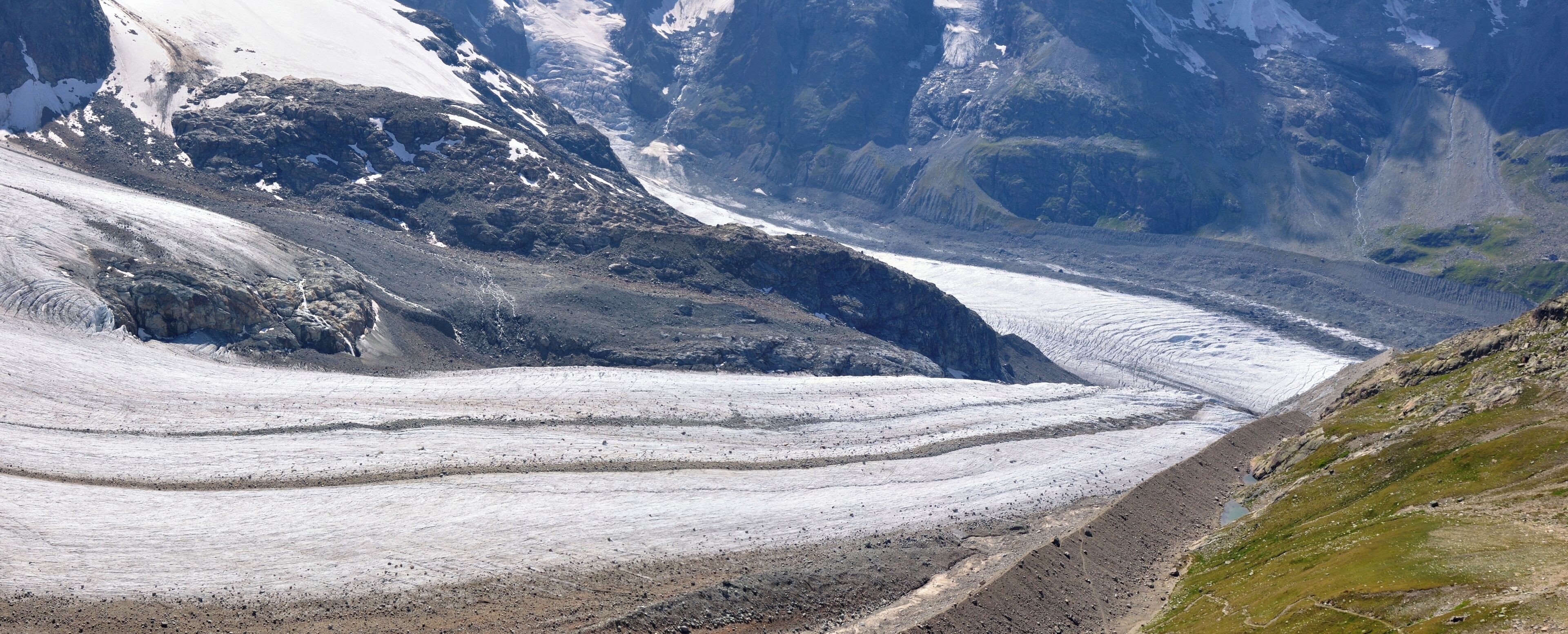 A glacier with a steep, rocky mountain in the background.
