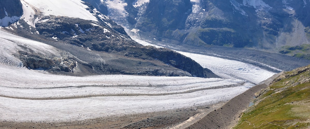 A glacier with a steep, rocky mountain in the background.