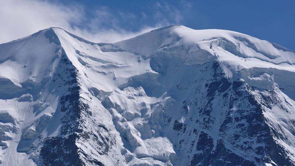 A snow-covered mountain with rugged terrain and a clear sky.
