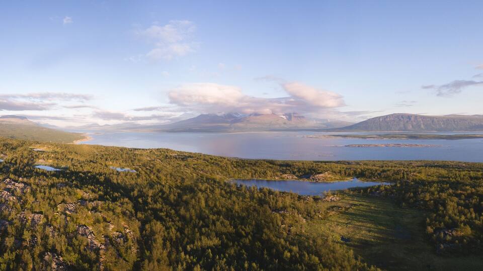A mountainous landscape with a lake and forested areas.