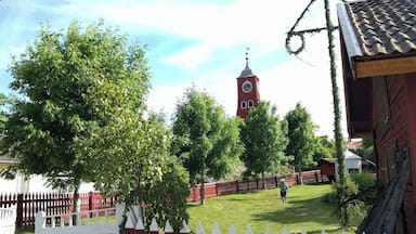 A red clock tower, a white lattice fence, and a red picket fence in a park.