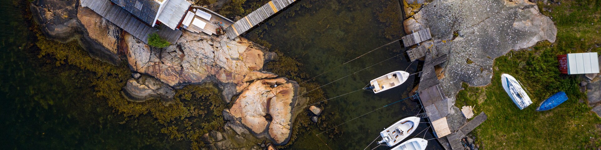 An aerial view of a rocky island with a dock, boats, and a small building.