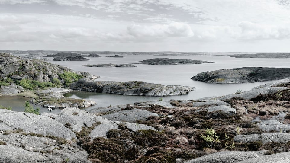 A rugged coastal landscape with rocky outcrops and a calm sea.