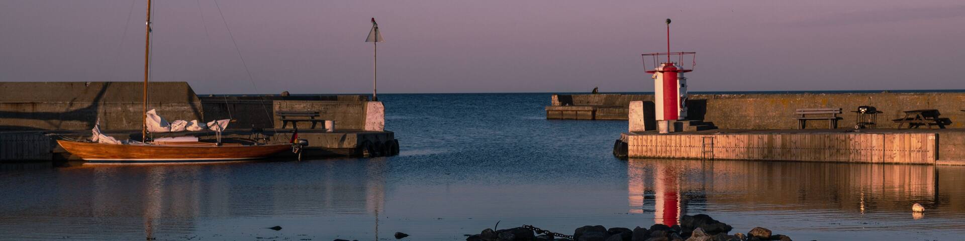 lighthouse in the harbor of brantevik at sunset
