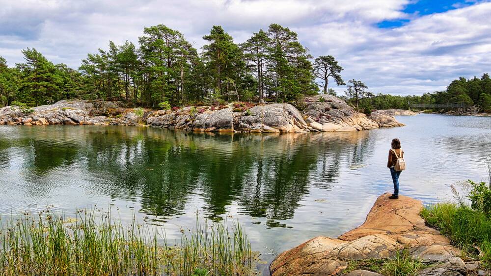 Wanderin beobachtet auf einer Felskuppe die gegenĂŒberliegende SchĂ€reninsel im Naturreservat Stendörren in Schweden