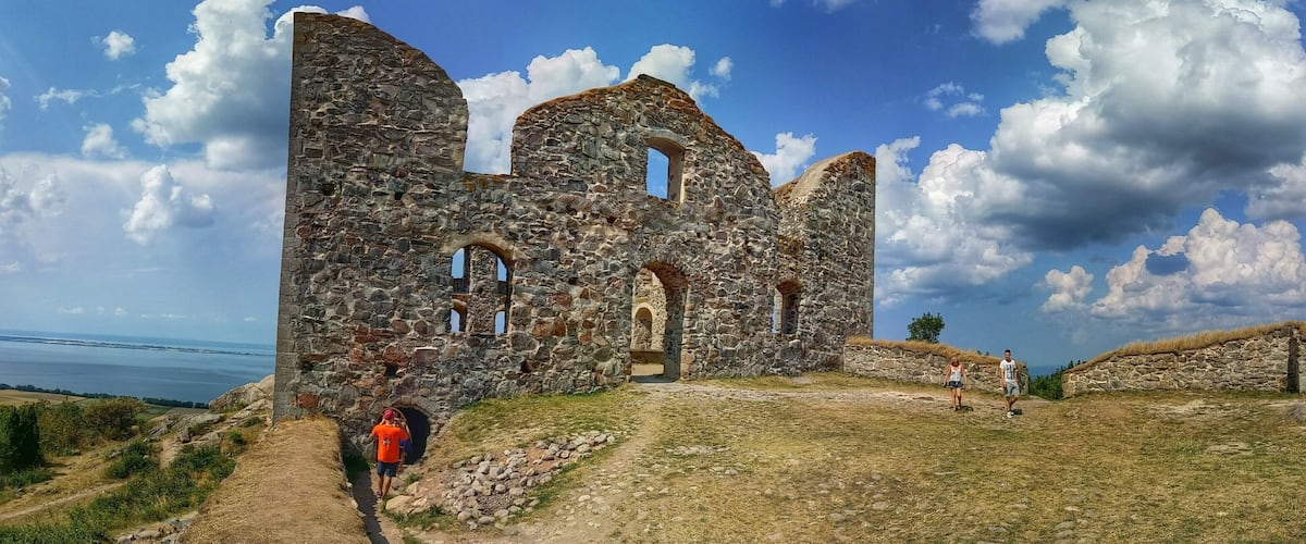 A stone ruin with arched openings and a clear view of the sea in the background.