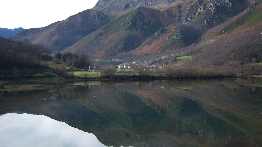Un paysage montagneux avec un lac qui reflète le décor environnant.